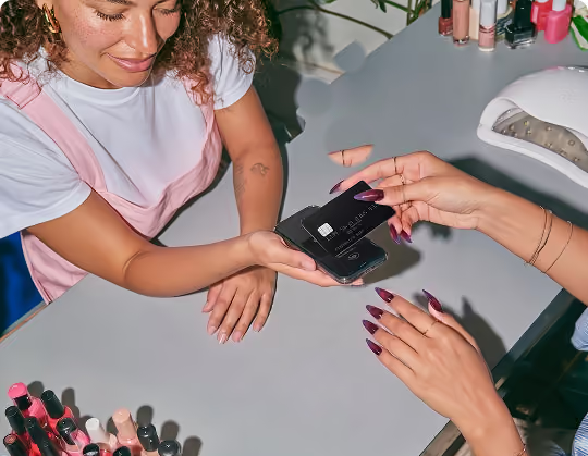 Salon client tapping a card on the stylist's phone